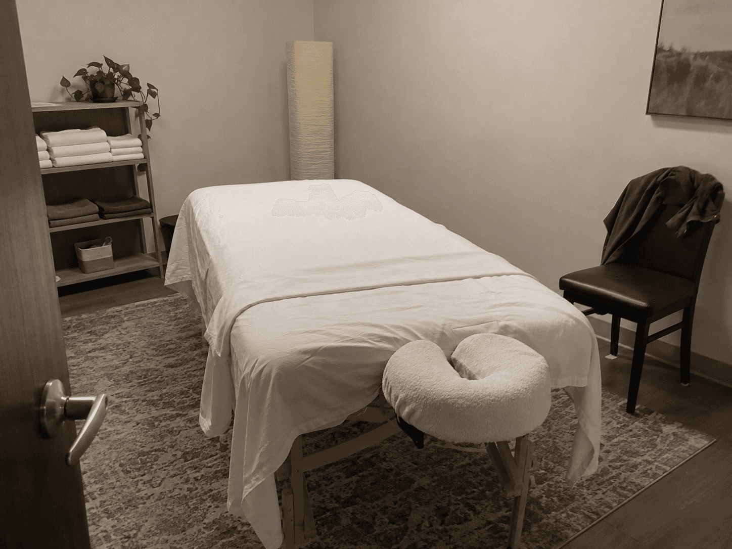 A clean covered massage table in a simple treatment room.