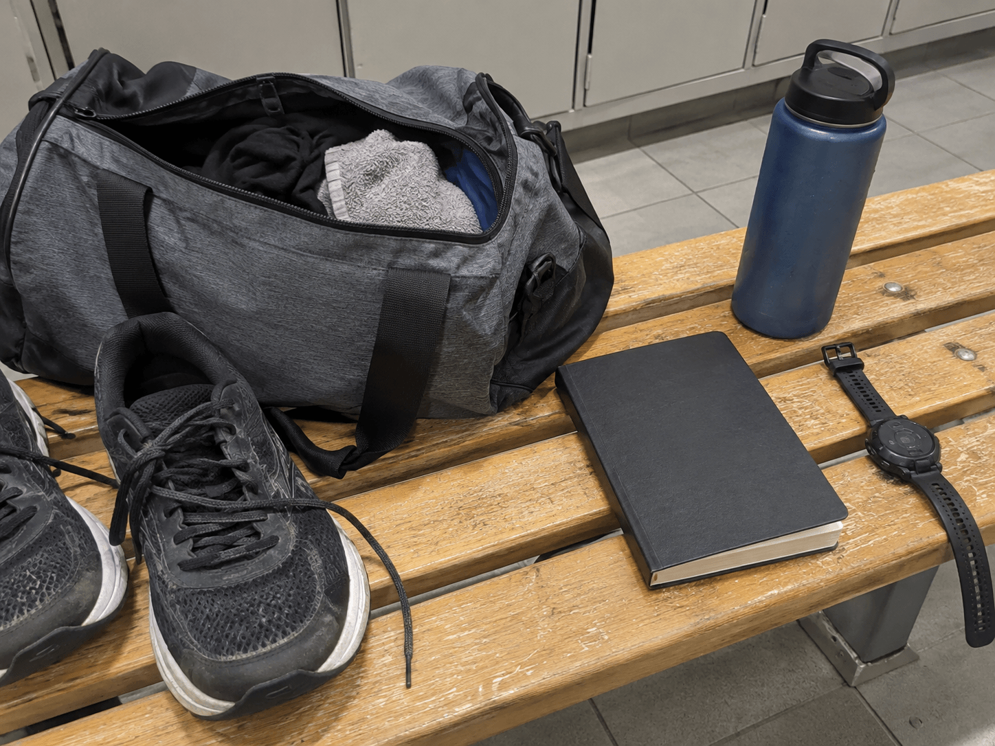 A water bottle and gym bag on a changing bench.