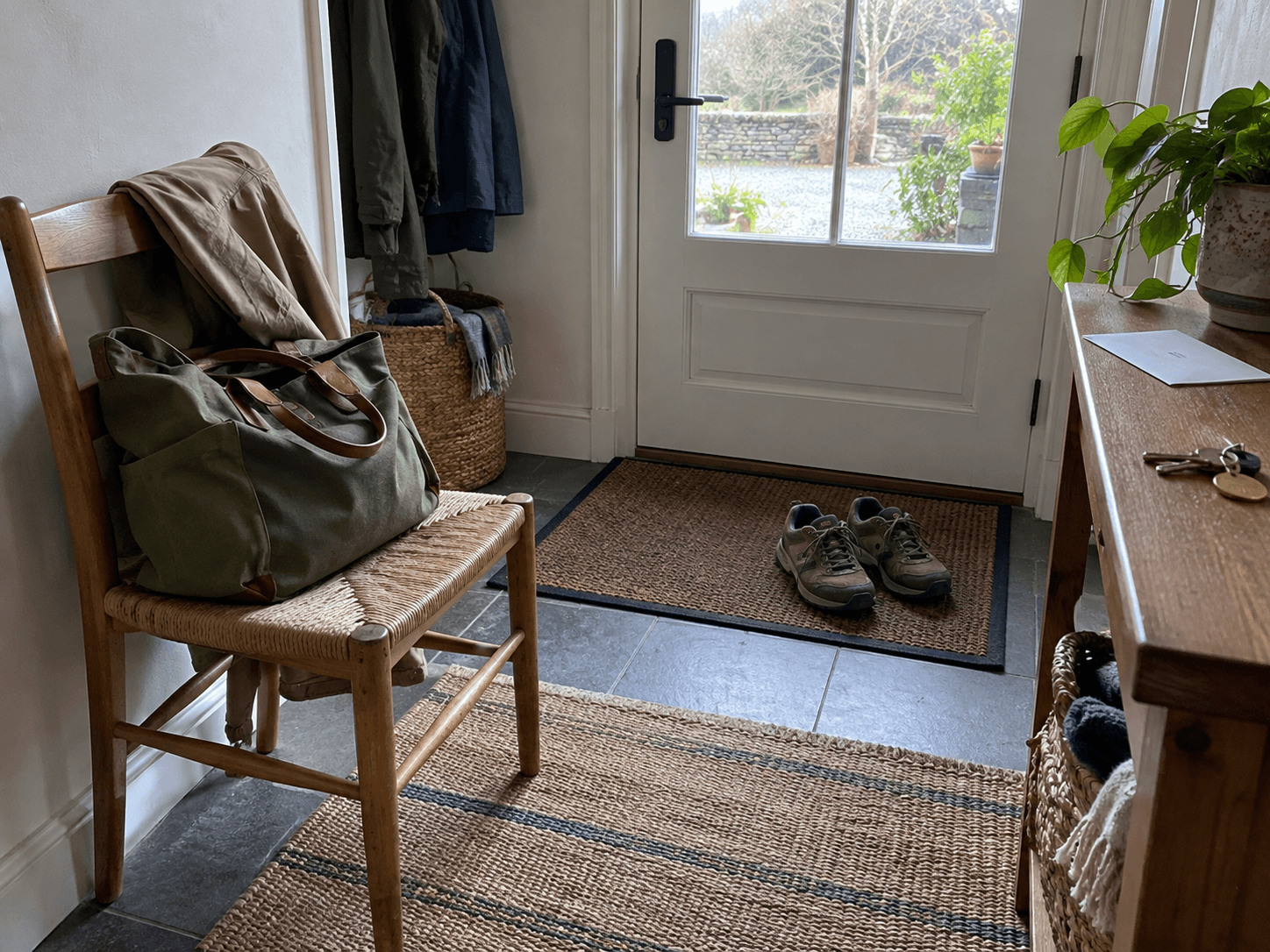 A packed green bag and jacket ready beside an entrance.