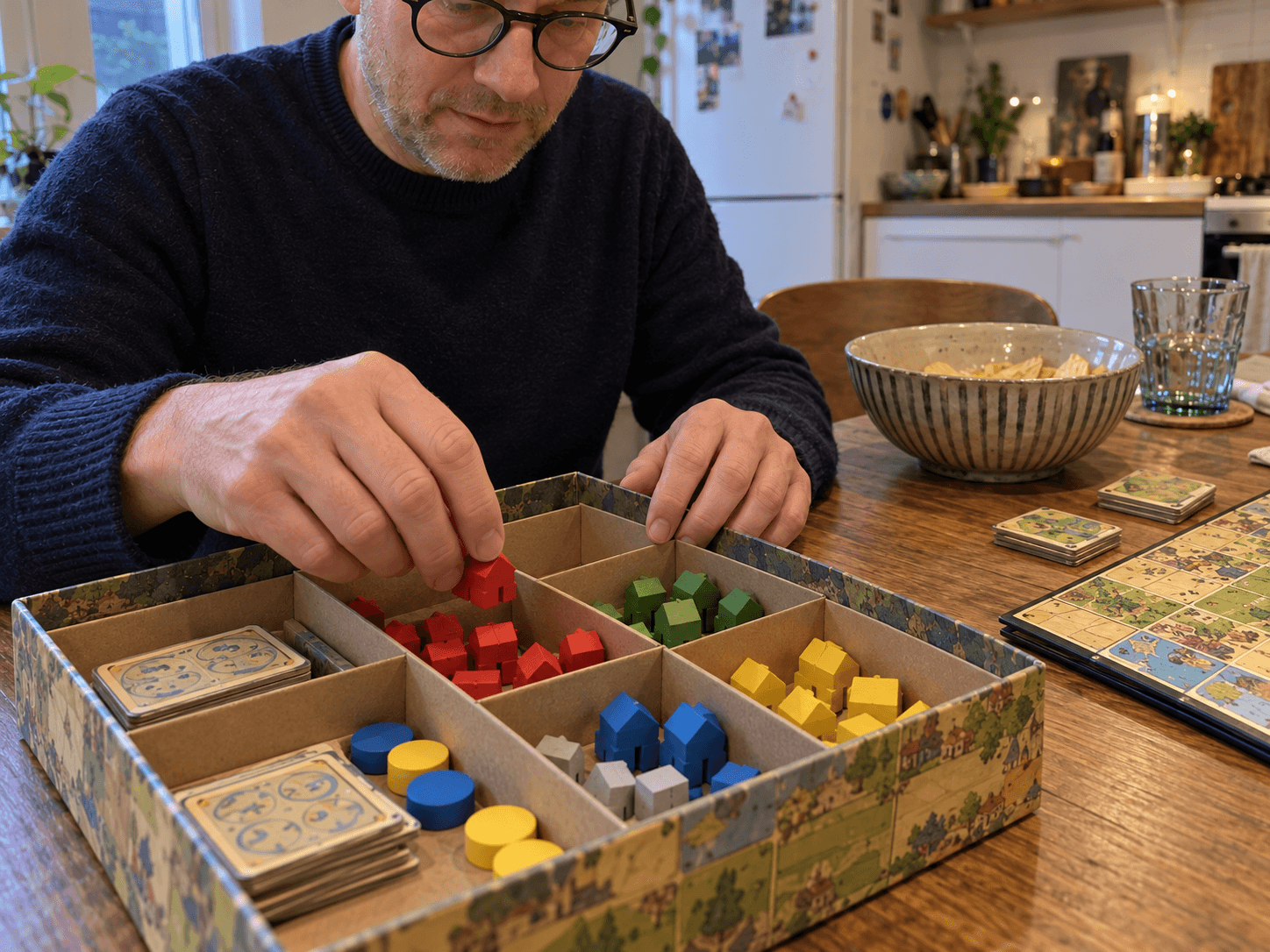 Coloured wooden game pieces being returned to separate compartments in a box after one finished game.