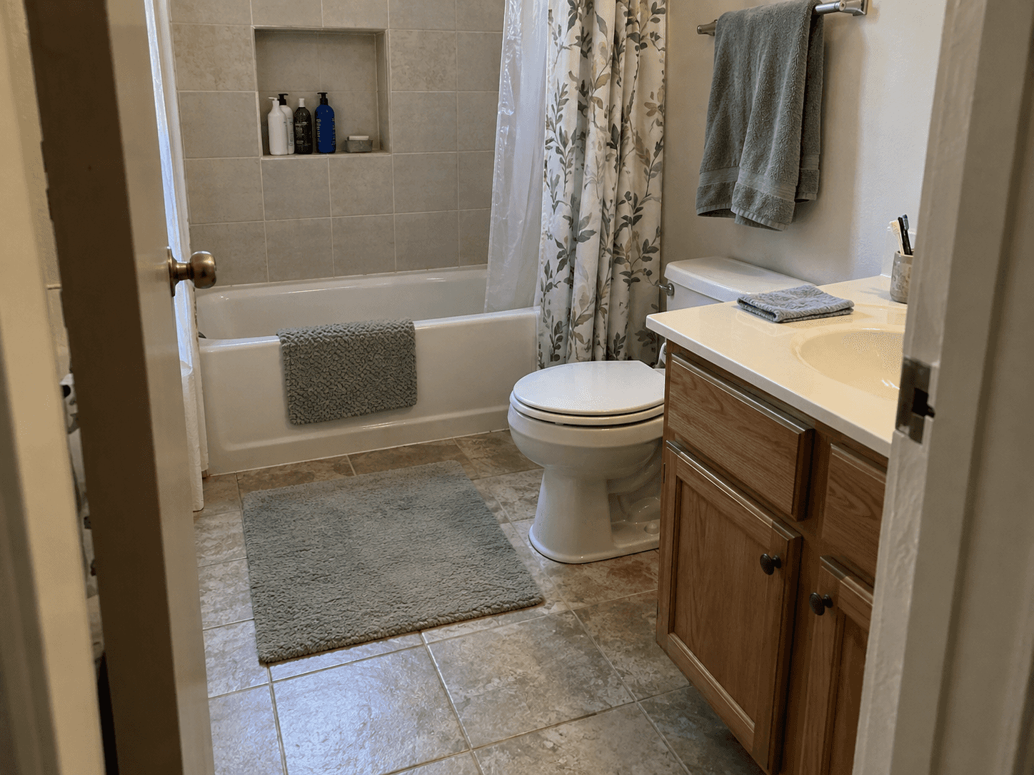 A dry bathroom floor with a flat bathmat and a towel on a rail.