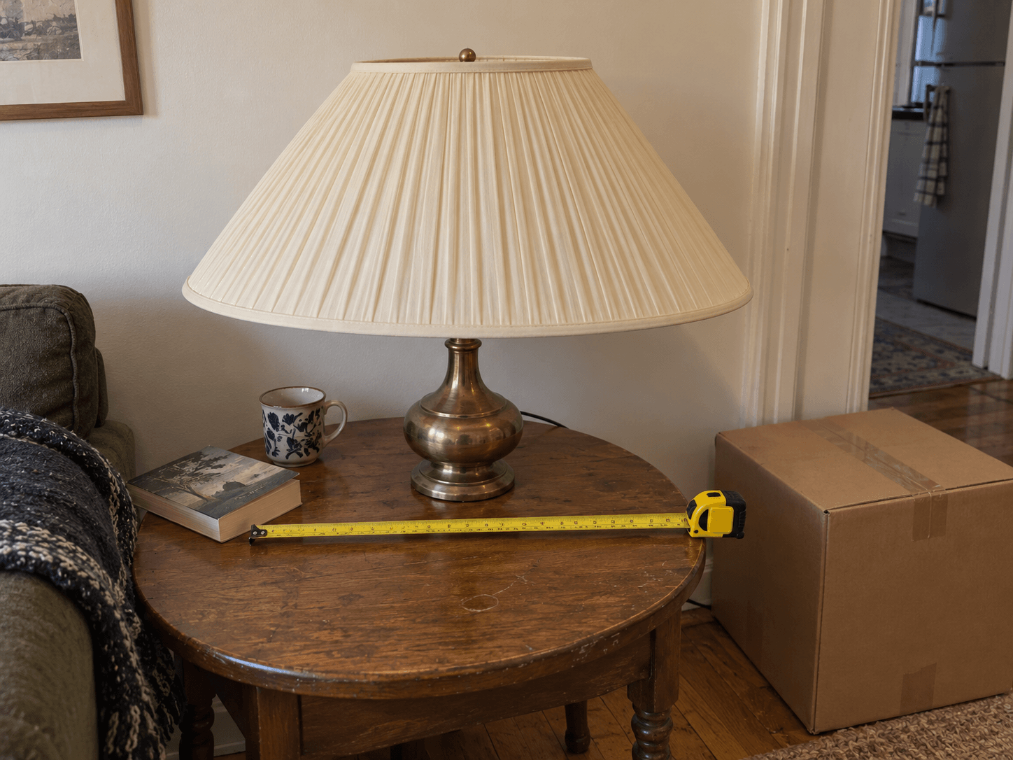 Owen's unusually wide lampshade on its lamp beside a tape measure in his flat before the move.