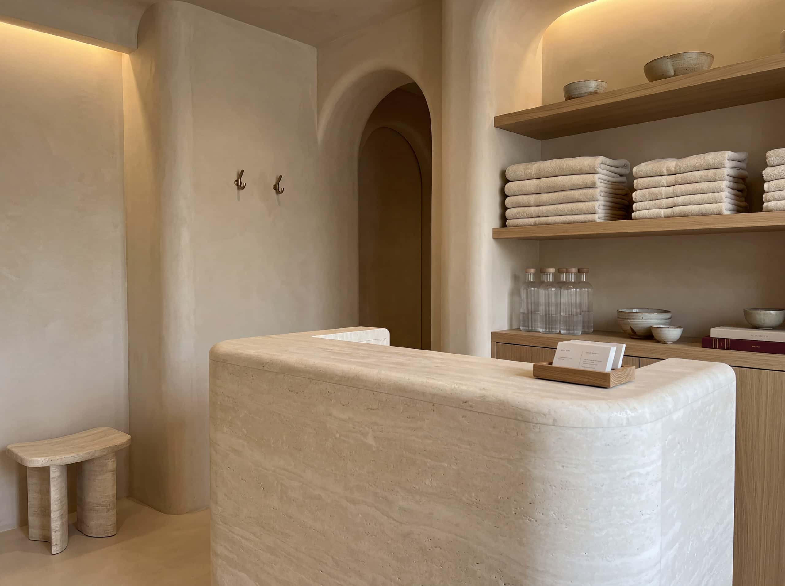 Vellum reception area with rounded travertine desk and warm microcement walls