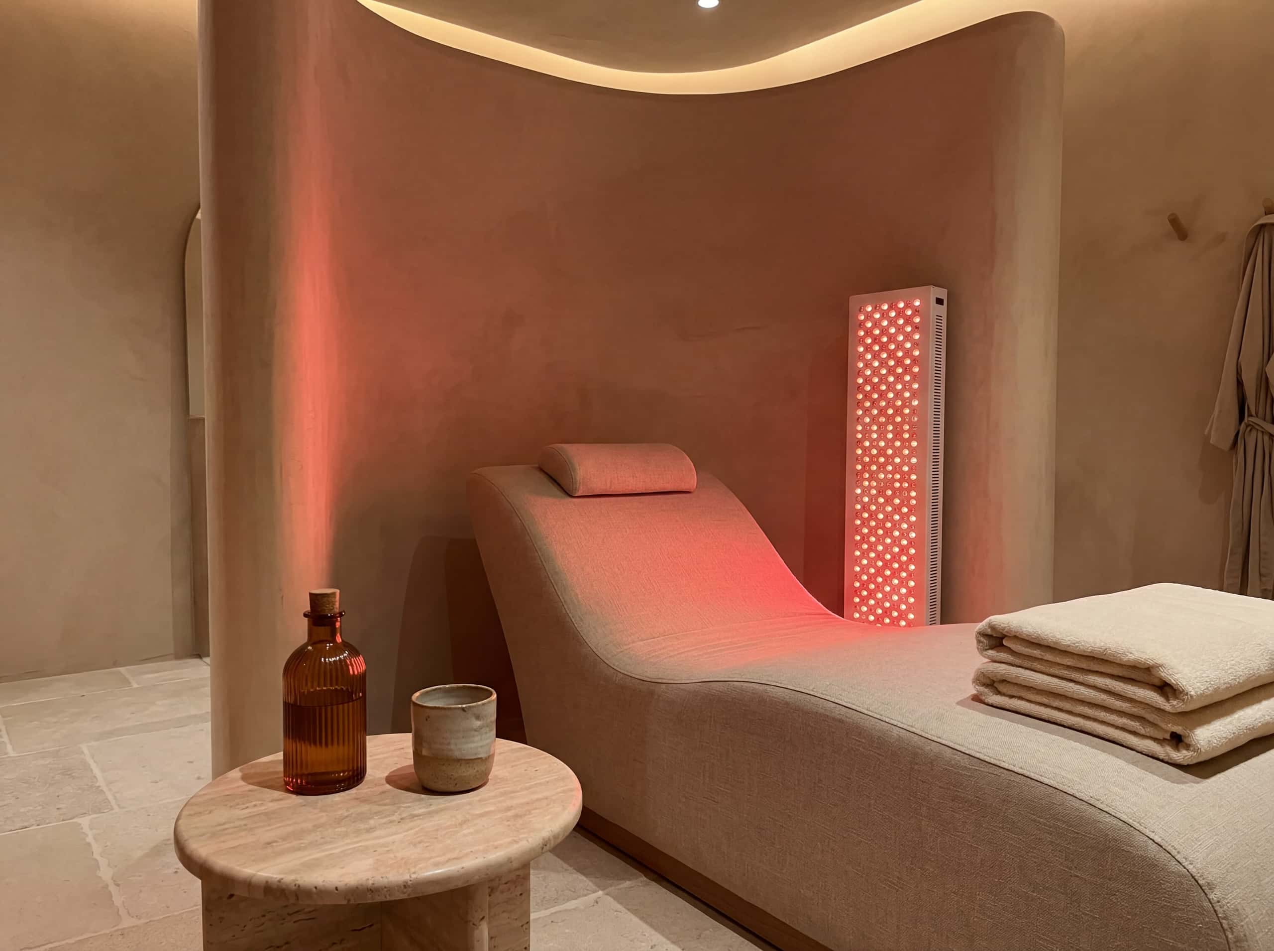 Red light therapy room with curved treatment bench and warm panel glow